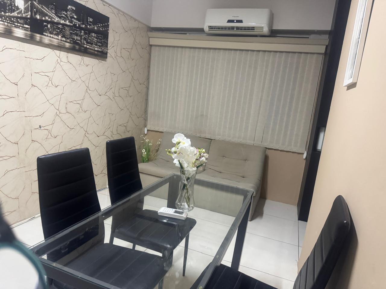 Sala de atendimento com mesa de vidro, cadeiras e sof&aacute; ao fundo