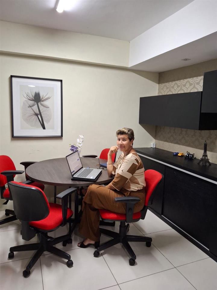 Dra. No&ecirc;mia Gomes sentada &agrave; mesa de atendimento